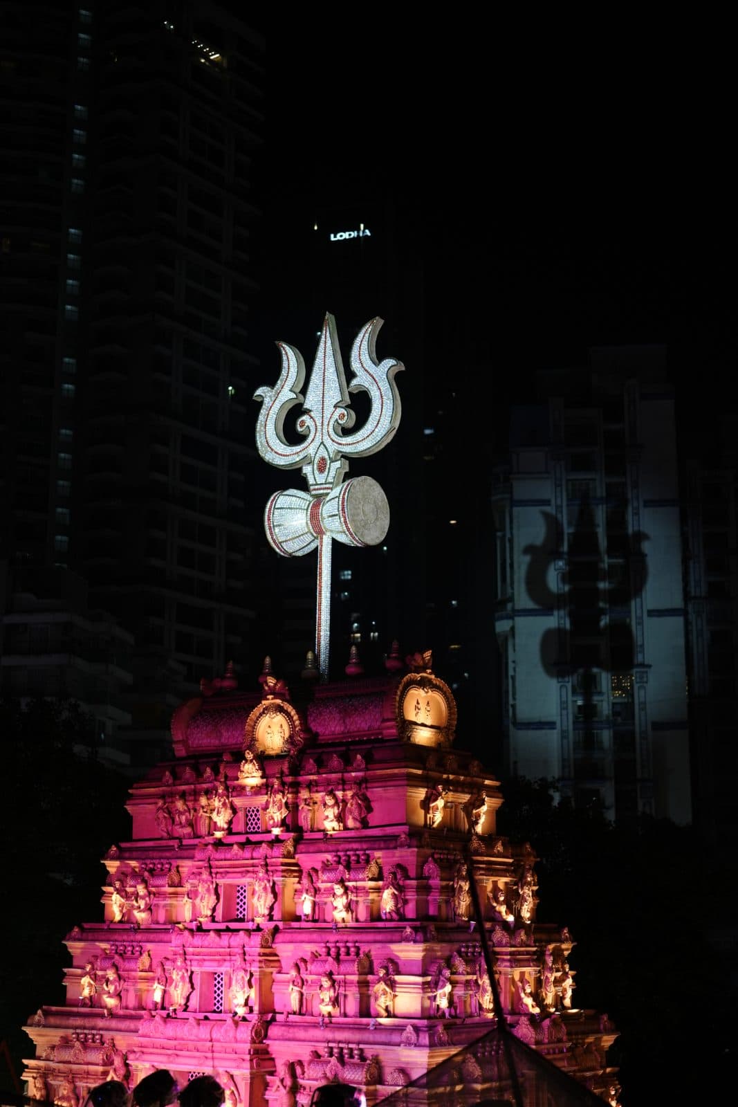 Illuminated trishul rising above the temple structure