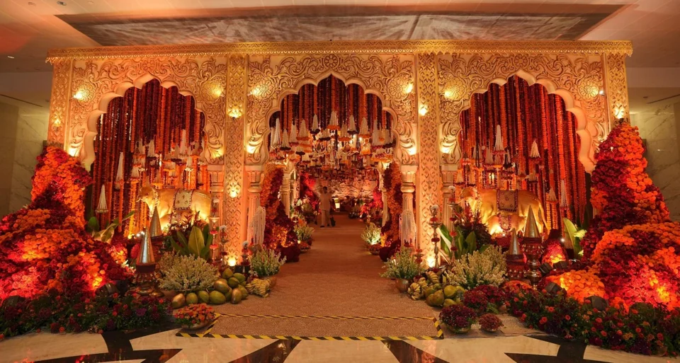 A warm red mandap with intricate floral and architectural details